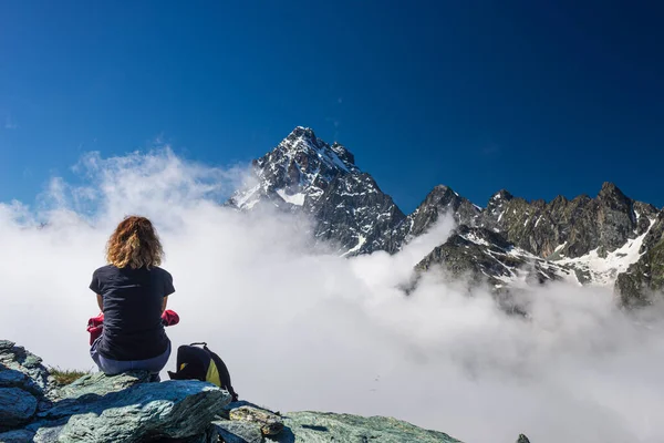 女性の高い山の頂上には 雲の上のビュー劇的な風景雄大な山のピークを見て 澄んだ青い空に休んで 夏のアクティビティフィットネス健康の自由成功 — ストック写真