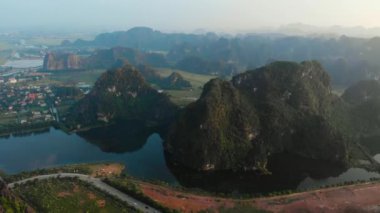 Hava: Günbatımında Kuzey Vietnam karst manzarası, Ninh Binh bölgesinin insansız hava aracı manzarası, Trang An Tam Coc turizm merkezi, UNESCO Dünya Mirası Alanı, eşsiz kireçtaşı zirveleri, pirinç tarlaları ve nehir manzarası