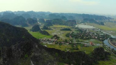 Hava: Kuzey Vietnam karst manzarası, Ninh Binh bölgesinin insansız hava aracı manzarası, Trang An Tam Coc turizm beldesi, eşsiz kireçtaşı zirveleri, pirinç tarlaları, nehir ve köyleri geçen yol.