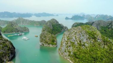 Hava: Ha Long Körfezi kaya tepeleri üzerinde uçmak, Vietnam 'daki ünlü seyahat noktaları. Tekneler ve kanodaki turistler eşsiz kireçtaşı zirveleri, denizdeki adalar, manzaralı körfezler ve yeşil orman arasında