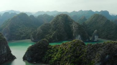Hava: Ha Long Körfezi kaya tepeleri üzerinde uçmak, Vietnam 'daki ünlü seyahat noktaları. Tekneler ve kanodaki turistler eşsiz kireçtaşı zirveleri, denizdeki adalar, manzaralı körfezler ve yeşil orman arasında