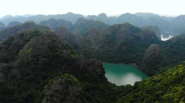 Hava: Ha Long Körfezi kaya tepeleri üzerinde uçmak, Vietnam 'daki ünlü seyahat noktaları. Tekneler ve kanodaki turistler eşsiz kireçtaşı zirveleri, denizdeki adalar, manzaralı körfezler ve yeşil orman arasında