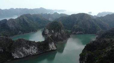 Hava: Ha Long Körfezi kaya tepeleri üzerinde uçmak, Vietnam 'daki ünlü seyahat noktaları. Tekneler ve kanodaki turistler eşsiz kireçtaşı zirveleri, denizdeki adalar, manzaralı körfezler ve yeşil orman arasında