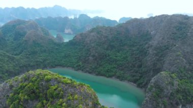 Havadan aşağı: Ha Long Körfezi kaya tepeleri üzerinde uçmak, Vietnam 'daki ünlü seyahat noktaları. Tekne ve kanodaki turistler denizdeki eşsiz kireçtaşı zirveleri, manzaralı körfezler ve yeşil ormanlar arasında