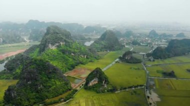 Hava: Kuzey Vietnam karst manzarası, Ninh Binh bölgesinin insansız hava aracı manzarası, Trang An Tam Coc turizm beldesi, eşsiz kireçtaşı zirveleri, pirinç tarlaları, nehir ve köyleri geçen yol.