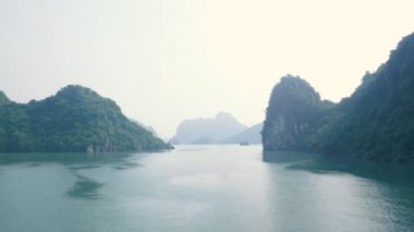 Ha Long Bay kaya zirveleri, Vietnam 'daki ünlü turizm merkezleri. Eşsiz kireçtaşı zirveleri ve denizdeki adalar, arka planda güneş doğuşu.
