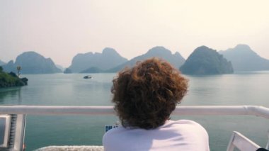 Vietnam Halong Körfezi 'nin eşsiz manzarasına bakan bir kadın. Ha Long Körfezi kaya zirvelerinde seyahat eden bir turist. Beyaz kadın ünlü şehir simgesinde tatilde eğleniyor..