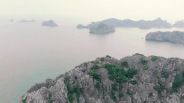 Günbatımında Cat Ba ve Ha Long Bay kaya tepelerinin üzerinde uçmak, Vietnam 'daki ünlü turizm merkezi. Eşsiz kireçtaşı zirveleri ve denizdeki adalar, manzaralı körfezler ve yeşil orman.