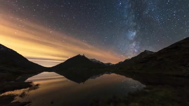 タイムラプス 銀河系と星が壮大なイタリアアルプスの上を回転します 山の中で美しい高山湖の夜空の反射 軌道を周回する飛行機の交通及び衛星 — ストック動画