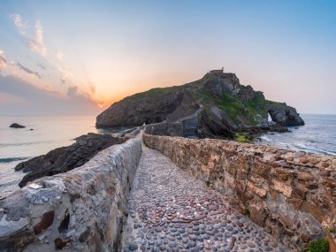 Günbatımında Gaztelugatxe adasına giden antik taş köprü Bask Bölgesi İspanya 'nın seyahat sembolü yalnızlık maneviyatı dramatik deniz manzarası