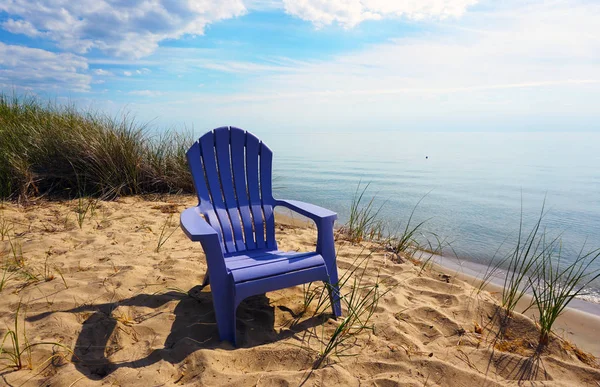 Michigan Gölü Beach yalnız sandalyeye. Mor şezlong su yakınlarındaki bir tepe üzerinde. Sandy kıyı ve yeşil çimen.