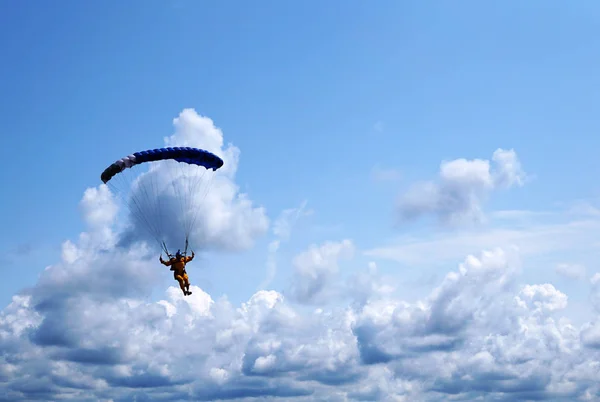 Skydiver arka plan mavi bir gökyüzü ve bulutlar, yakın çekim bir paraşüt koyu mavi küçük gölgelik altında. Gökyüzü ve fırtınalı bulutlar karşı paraşüt ile paraşütçü silüeti.                 
