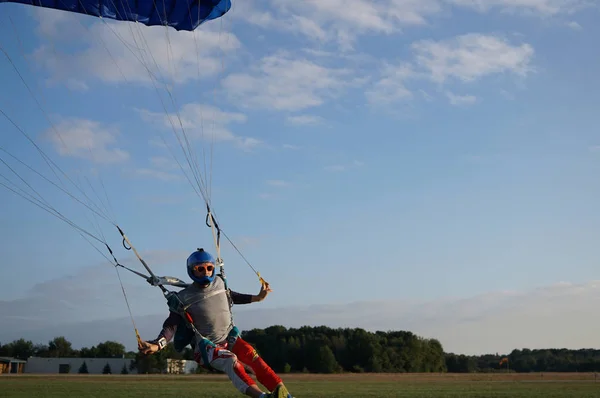 Skydiver küçük gölgelik bir paraşüt Havaalanı, açılış bir koyu mavi altında yakın çekim. Bir parachuter arka planı ormanlar ve binalar yüksek hızlı iniş.