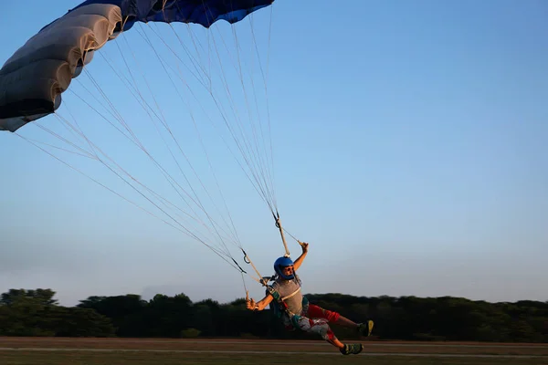 Skydiver küçük gölgelik bir paraşüt Havaalanı, açılış bir koyu mavi altında yakın çekim. Bir parachuter arka planı ormanlar ve binalar yüksek hızlı iniş.