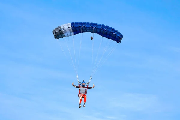 Paracaidista con un paracaídas azul oscuro en el fondo un cielo azul — Foto de Stock