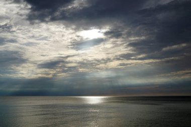 Karanlık gün batımı. Güneş ışınları gölün yüzeyinde parlıyor.