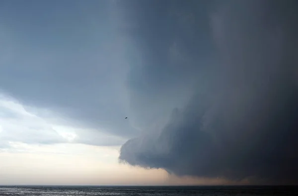 Thoundstorm with Dark clouds coming over the calm lake with an alone bird flying in the sky to the storm — Stock Photo, Image