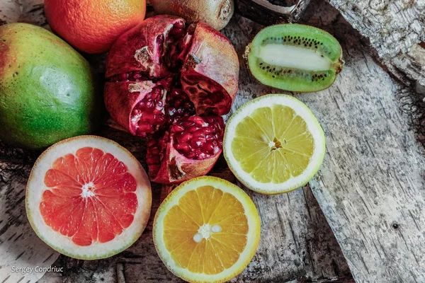 Juicy ripe fruit in a cut on a background of a birch bark. Orange, pomegranate, kiwi, grapefruit, lemon and mango. Food photography. Photo background.Fruit.