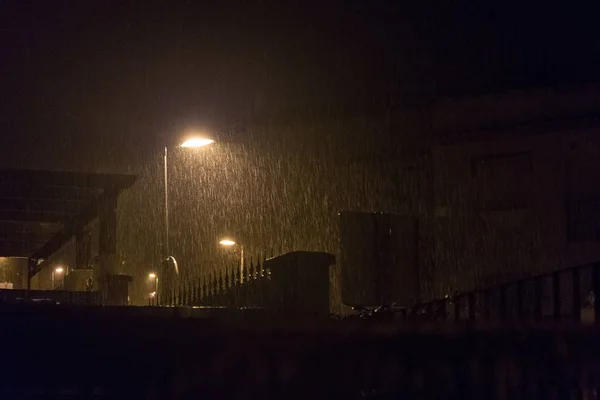 Bir elektrik direği gece ışığında şiddetli yağmur