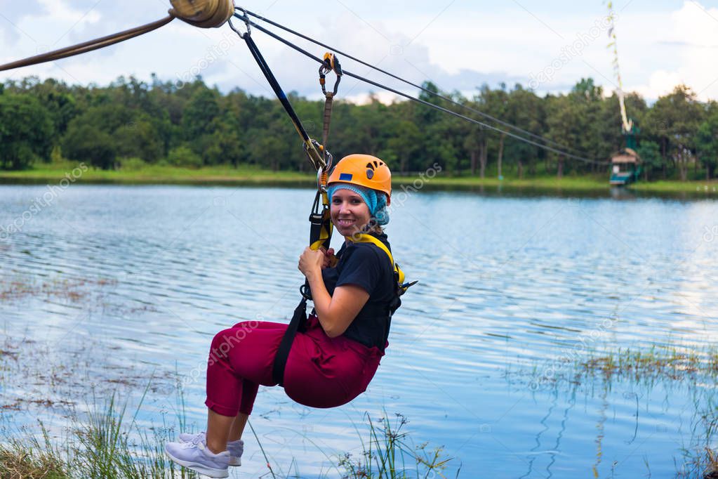 Young girl goes through a lagoon on zip line in Chiang Mai in Thailand