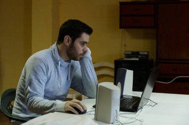 Genç adam cep telefonunu kullanarak tablet, dizüstü bilgisayar ve kulaklıklar