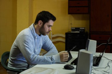 Genç adam cep telefonunu kullanarak tablet, dizüstü bilgisayar ve kulaklıklar