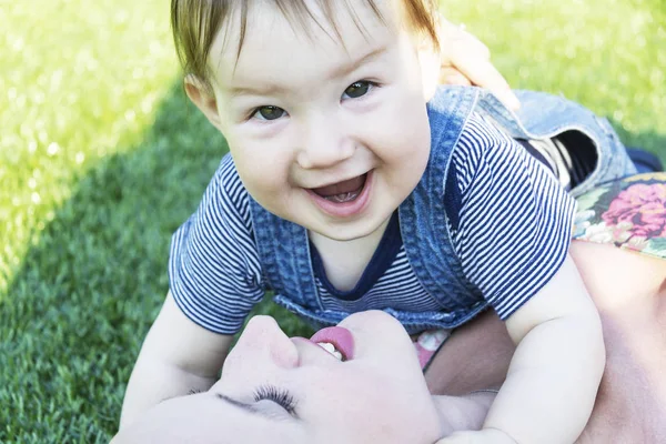 Maminka a děťátko leží na zelené trávě — Stock fotografie
