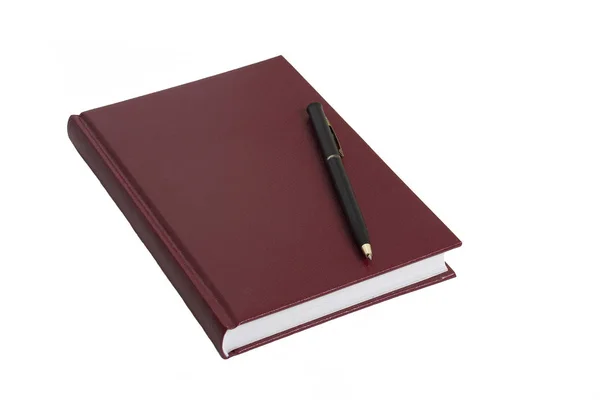 De Bordeaux notebook en zwarte pen liggen op een witte tafel. — Stockfoto