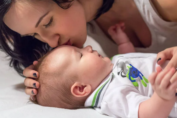 Mladá krásná matka brunetka líbání její malý syn — Stock fotografie