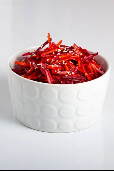 Beyaz derin bir tabakta elma, havuç ve limon suyu, susam ve bitkisel yağ ile sebze salatası