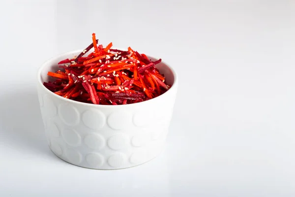 Beyaz derin bir tabakta elma, havuç ve limon suyu, susam ve bitkisel yağ ile sebze salatası