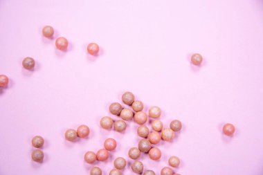 Pembe arka plandaki bir masaya dağılmış allık topları. Yüksek kalite fotoğraf