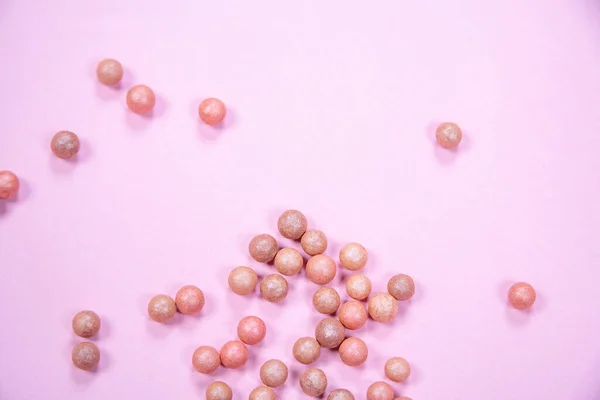 Pembe arka plandaki bir masaya dağılmış allık topları. Yüksek kalite fotoğraf