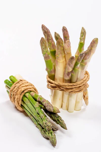 Gri arka planda gri bir iple bağlanmış yeşil ve beyaz kuşkonmaz. Yüksek kalite fotoğraf