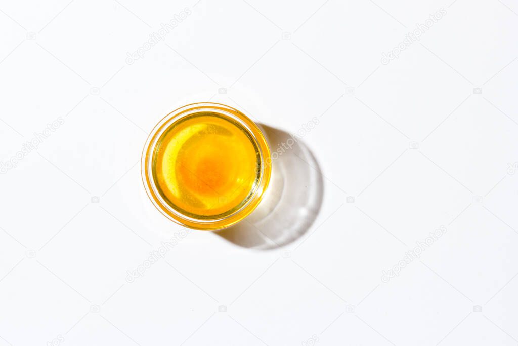 Honey in a small glass plate on a white background top view. Nearby lies a wooden spoon. High quality photo