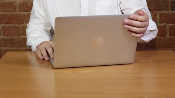 Un homme en chemise blanche à une table devant un ordinateur portable — Video