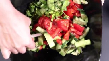 Eller yakın plan sebze salatasını karıştırır. Üst görünüm