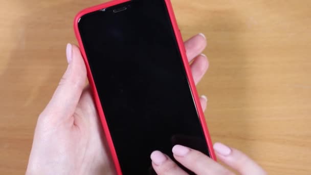 Las manos femeninas sostienen un teléfono inteligente en una caja roja. Vista superior de cerca — Vídeos de Stock