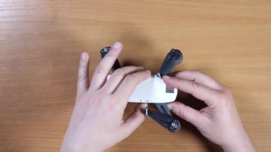 Erkek eller açılır ve düzleşir ve yakın plan beyaz bir dronun kanatlarını çevirir. Üst Görünüm Yüksek Kaliteli FullHD görüntüleri