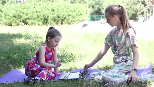 二人の十代の女の子は木の木陰の公園で屋外でチェスをします 高品質のフルHd映像 — ストック動画