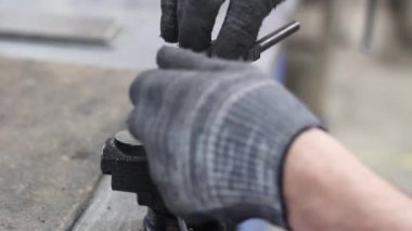 Gri eldivenli bir fabrika işçisinin elleri mengeneye sıkıştırılmış metal bir parçaya iplik yapıyor. Yüksek kaliteli FullHD görüntüler
