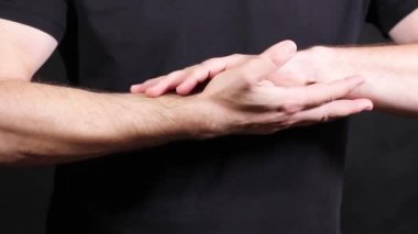 Beyaz erkek, kısa kollu siyah bir tişört giymiş ellerini yumruğa sıkıştırıyor ve izole edilmiş bir şekilde yakın çekim yapıyor. Yüksek kaliteli FullHD görüntüler