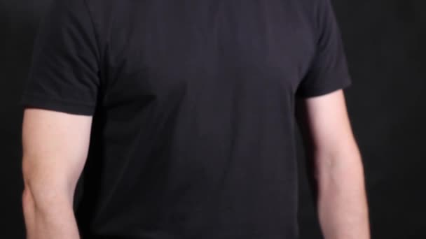 Manos masculinas caucásicas en una camiseta negra de manga corta, tirando de un puño — Vídeos de Stock