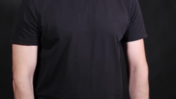 Mãos masculinas caucasianas em uma camiseta preta de manga curta, puxando um punho — Vídeo de Stock
