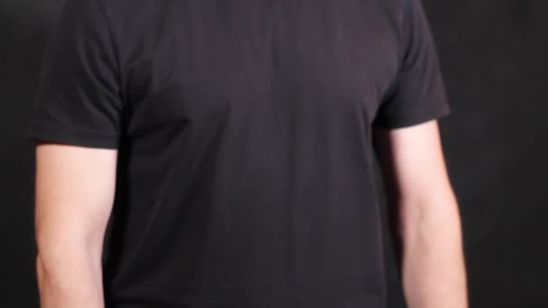 Mani maschili caucasiche in una maglietta nera a maniche corte, tirando un pugno — Video Stock