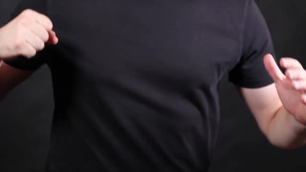 Biały mężczyzna w czarnej koszulce z krótkim rękawem, ciągnący pięść — Wideo stockowe