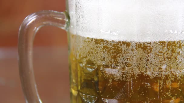 Cerveja em uma caneca de vidro grande com espuma alta muito de perto — Vídeo de Stock
