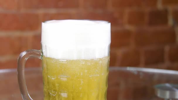 Cerveza en una taza de vidrio grande con espuma alta muy de cerca — Vídeos de Stock