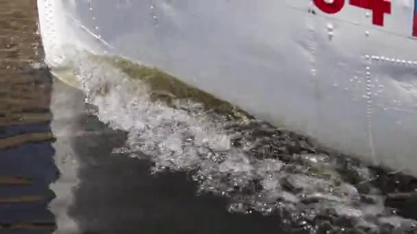 Een metalen boot drijft op de rivier en creëert golven van dichtbij — Stockvideo