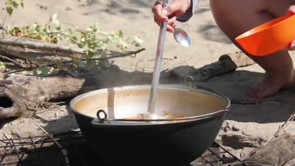 콩을 넣은 파파야는 자연적으로 모닥불 위에서 금속 가마솥 속에서 요리된다 — 비디오